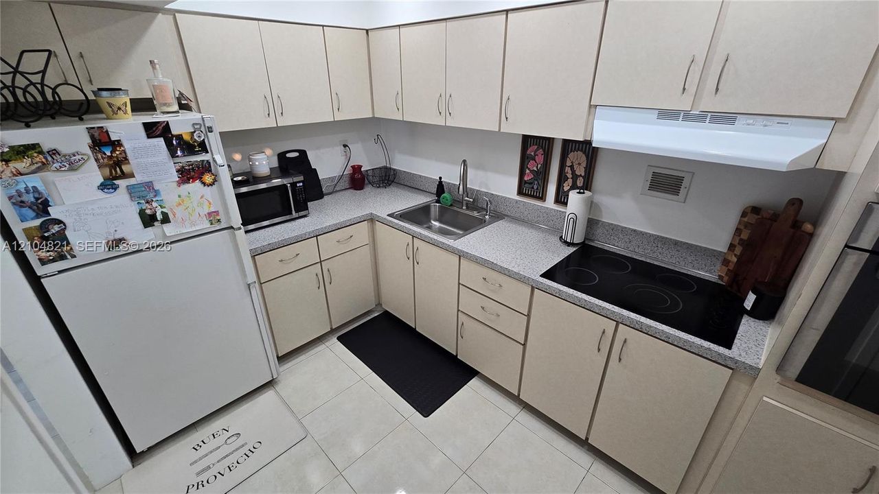 U-shaped kitchen with light-toned cabinetry, light-colored countertops, and a tile floor