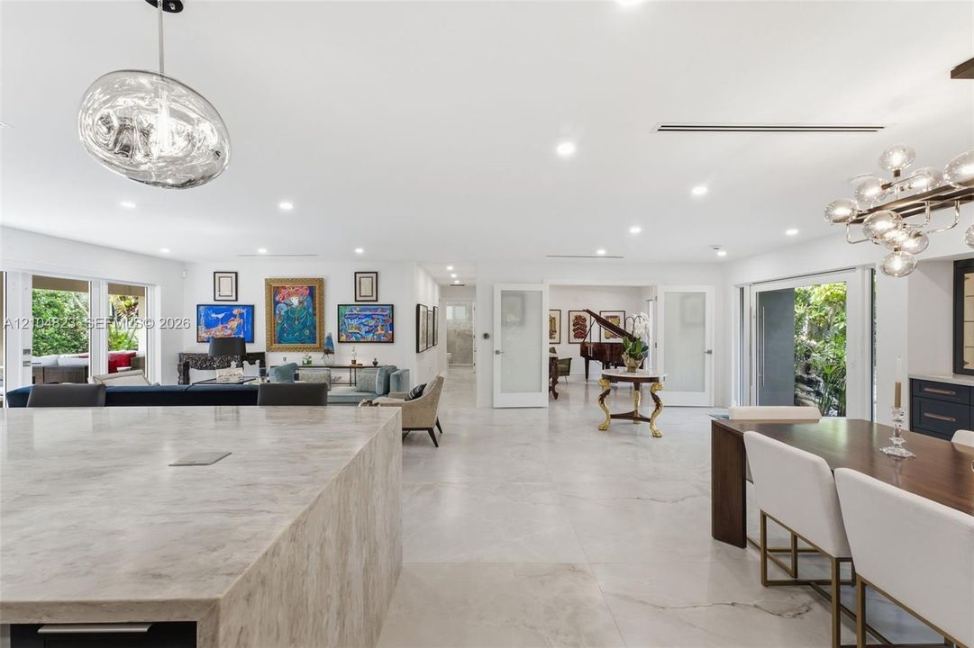 Recessed lighting throughout, wide plank tile flooring, expansive sliding glass doors, built-in cabinetry, and a contemporary chandelier