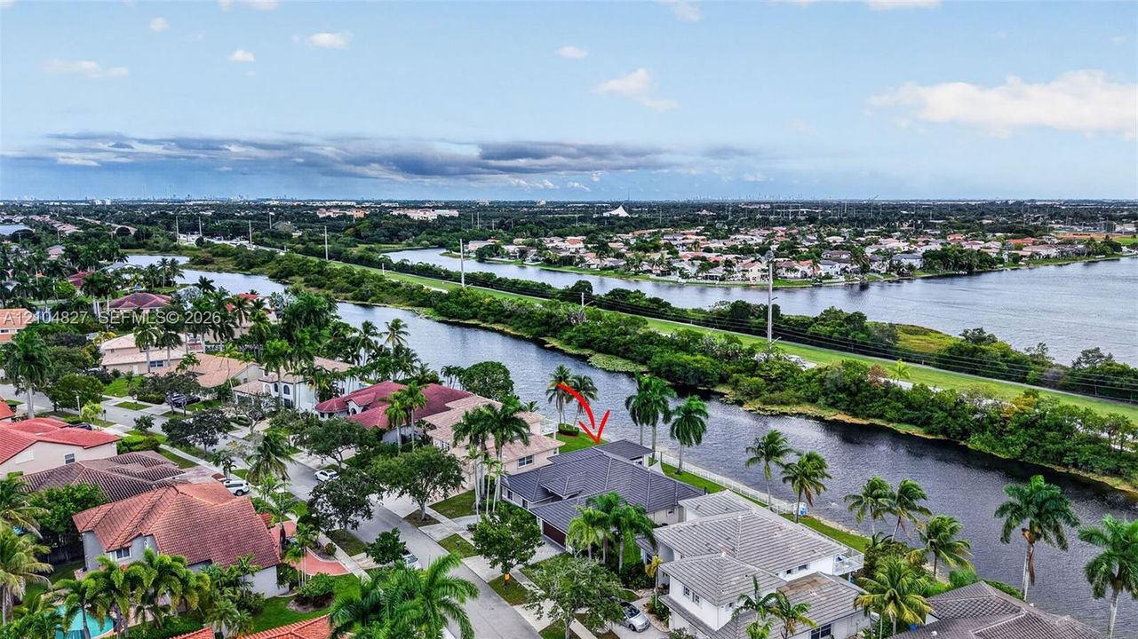 Aerial perspective featuring a waterfront property situated along a canal with mature palm trees and direct waterway access