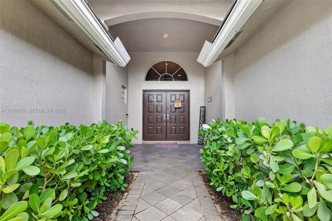 Covered entryway featuring a double-door entrance with a semi-circular transom window, vaulted ceiling, and stone-tiled flooring