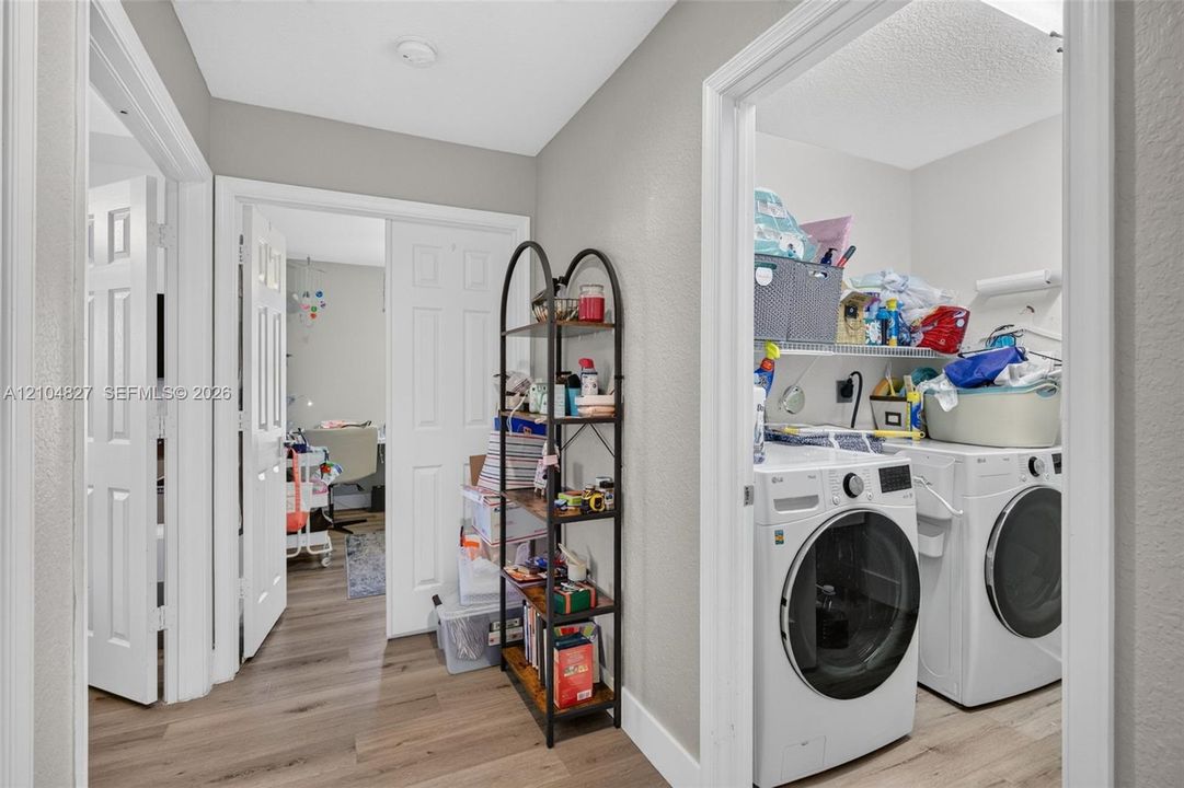 Dedicated laundry area featuring wood-finish flooring and built-in wire shelving
