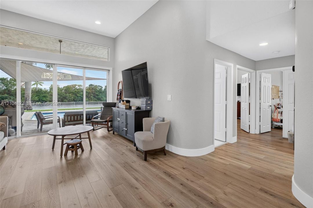 Open-concept interior featuring high ceilings, wood-finish flooring, recessed lighting, and expansive sliding glass doors
