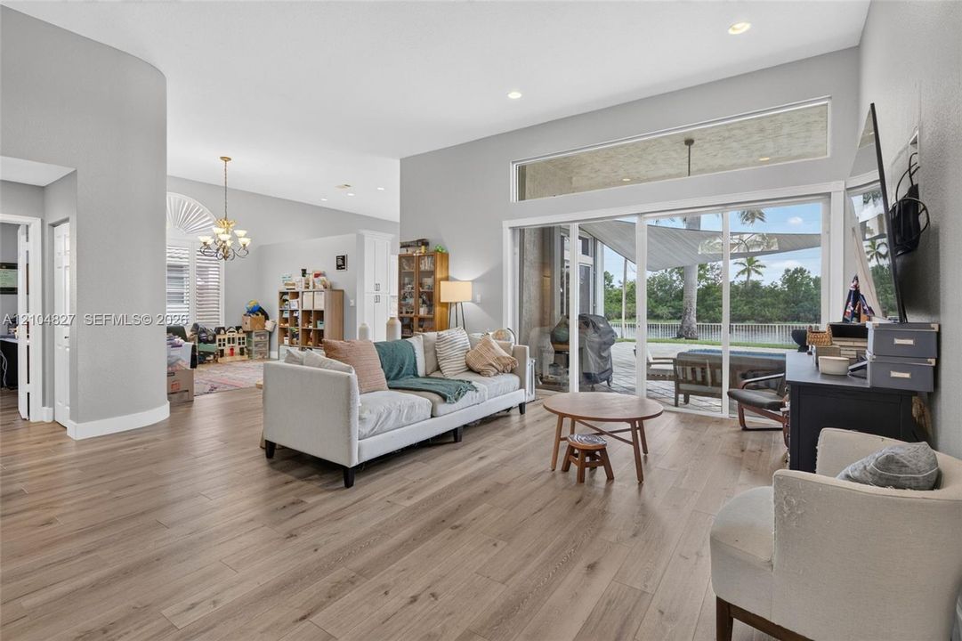 Open-concept living space featuring wood-finish flooring, recessed lighting, expansive sliding glass doors, a transom window, and a curved architectural wall detail