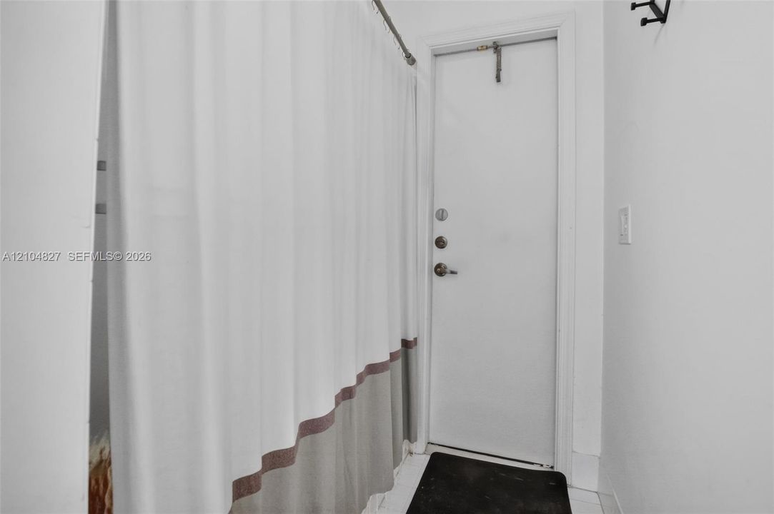 Solid-core interior door with a multi-point locking deadbolt system, adjustable overhead tension rod, and wall-mounted metal coat hook