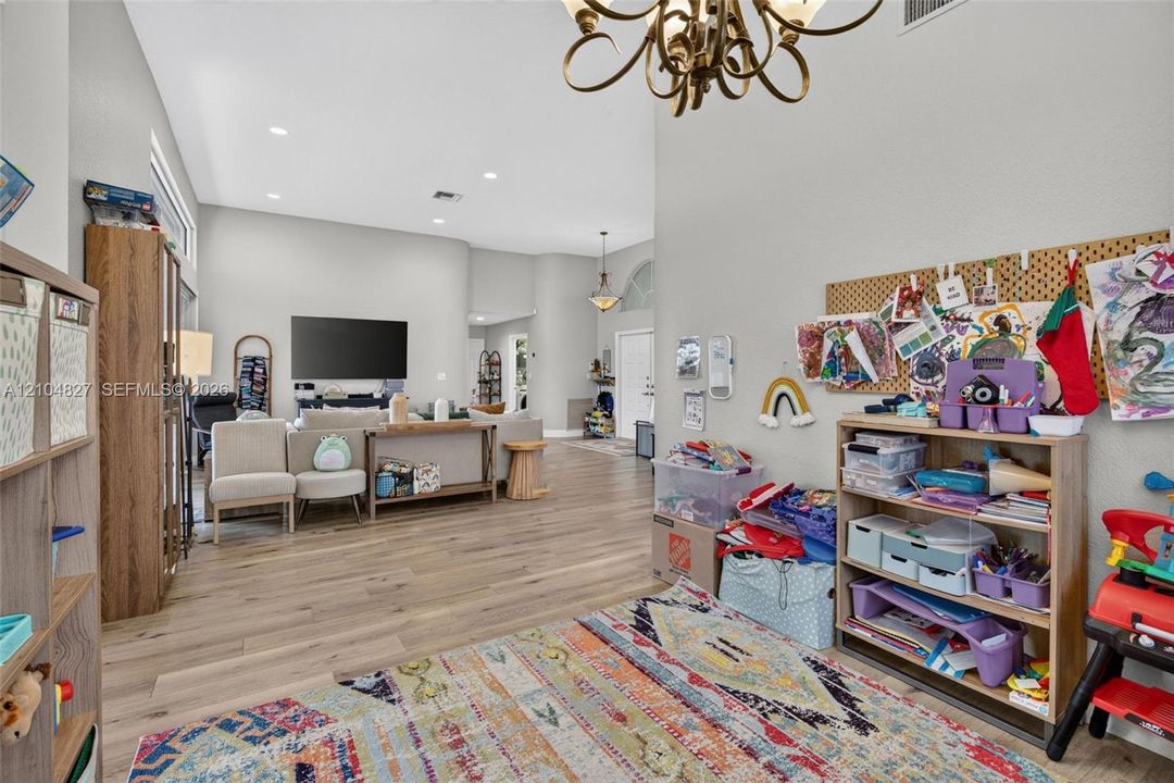 High-volume ceilings, wood-finish flooring, recessed lighting, and ornate metal chandelier