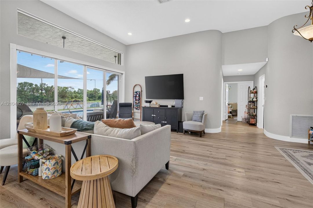 High ceilings with recessed lighting, wood-finish flooring, expansive sliding glass doors, transom windows, and curved architectural wall detailing