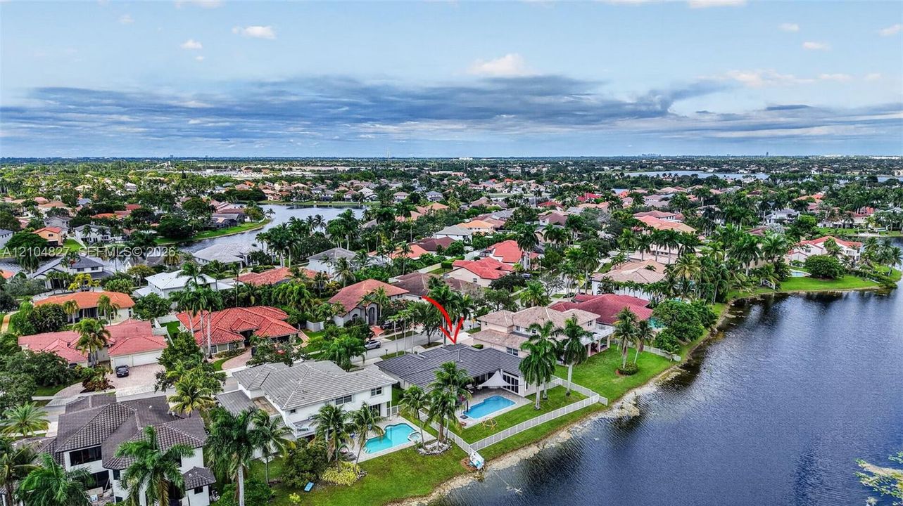 Waterfront property featuring a private swimming pool, expansive rear lawn, and mature palm trees