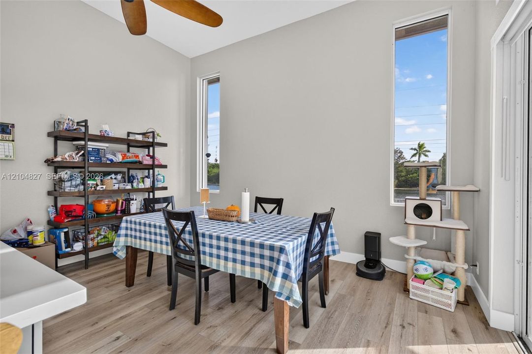 High-ceilinged area featuring wood-finish flooring, dual vertical windows, and a ceiling fan