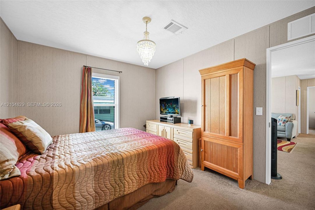 Neutral-toned interior walls featuring vertical paneling, neutral carpeting, and a crystal-style chandelier fixture