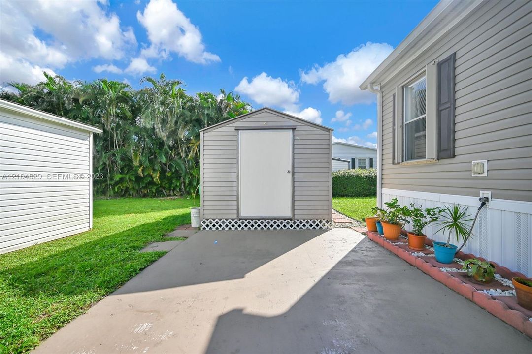 Exterior space featuring a concrete patio, a detached metal storage shed, and a raised concrete border planter