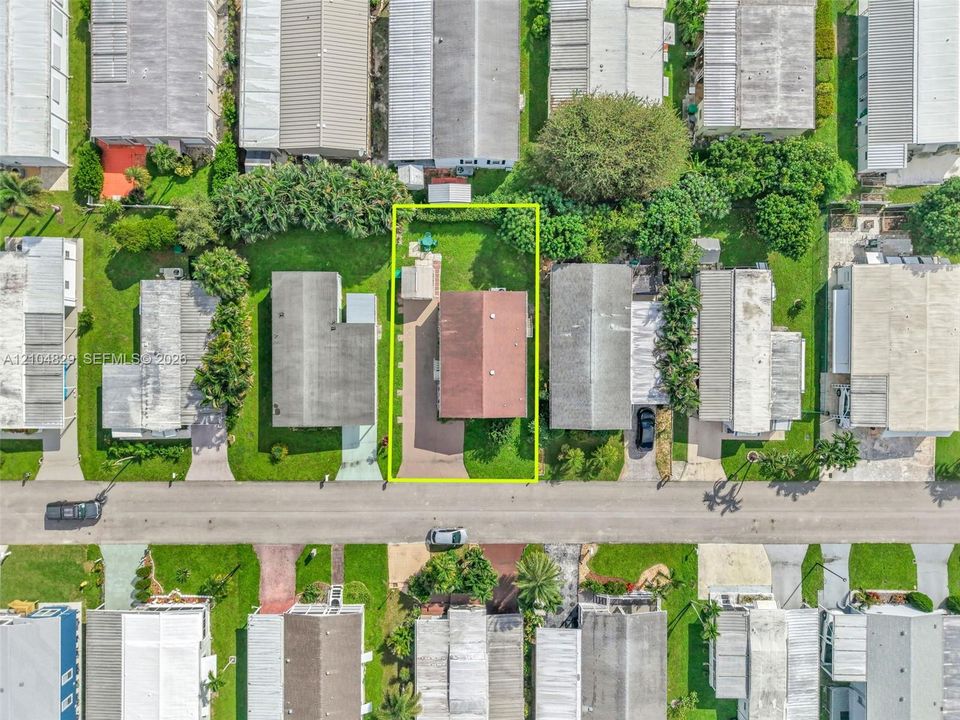 Aerial perspective of a property featuring a paved driveway, a detached storage structure, and a perimeter of mature landscaping