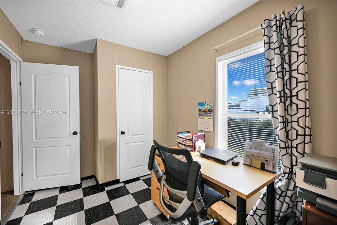 Room featuring a black and white checkered floor, two interior doors with arched top panels, and a single-hung window