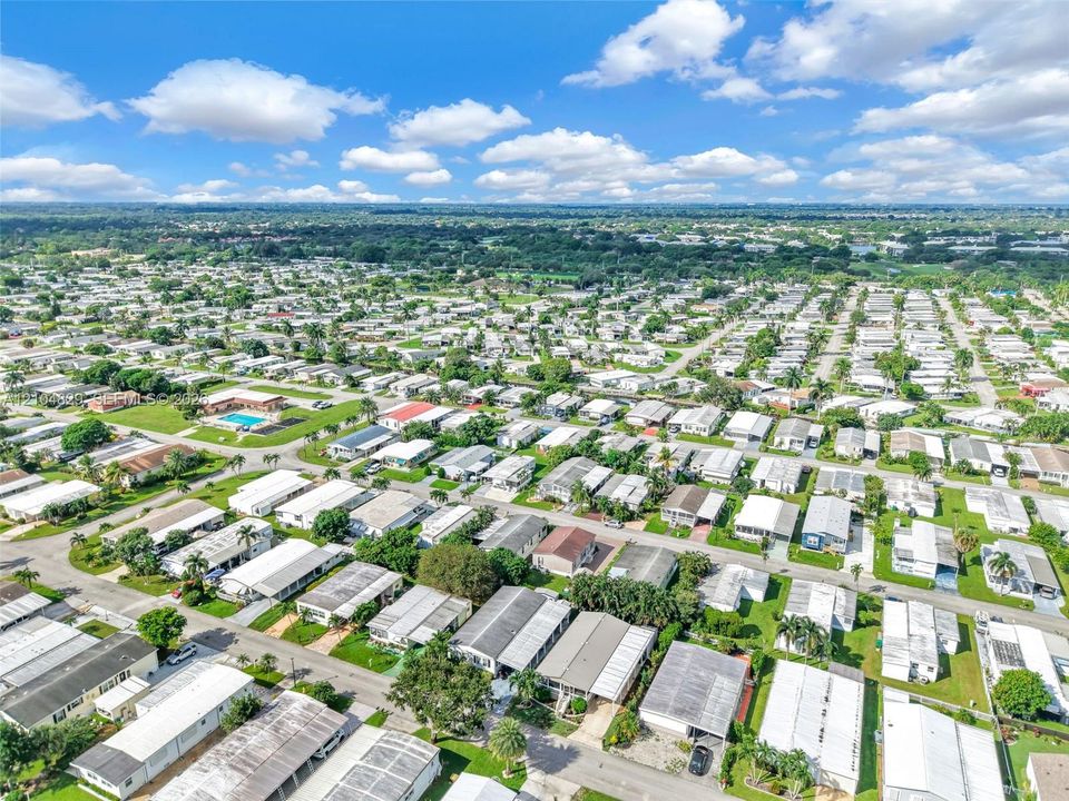 Aerial perspective of the residential community featuring paved street networks, established landscaping, and a central swimming pool facility