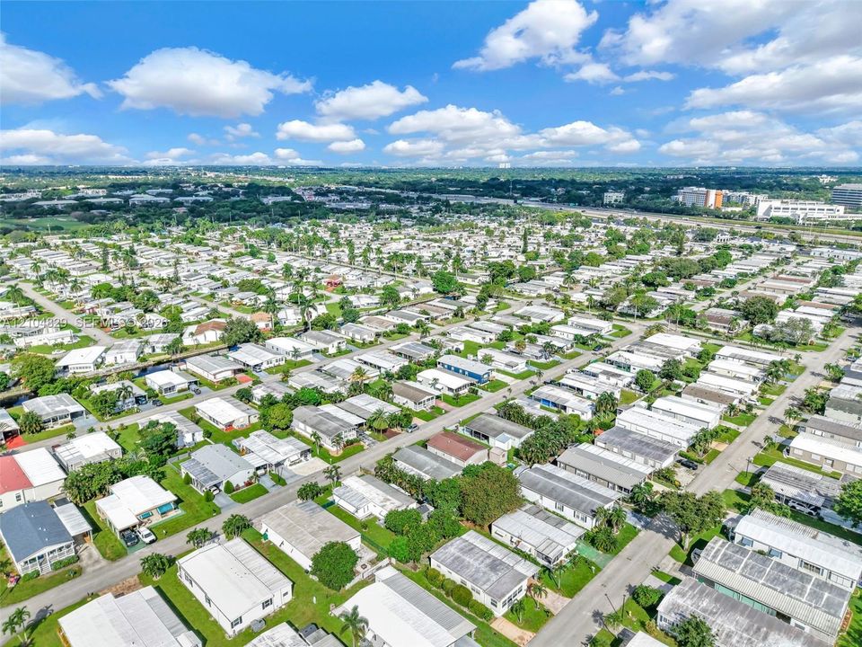 Aerial perspective of a planned community featuring paved street grids, manicured lawns, and mature landscaping