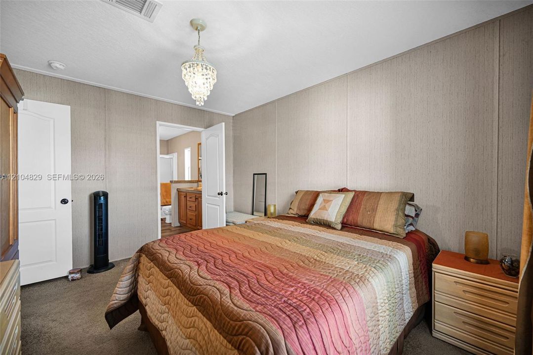 Neutral wall paneling, carpeting, white interior doors with brushed hardware, and a crystal-style chandelier fixture
