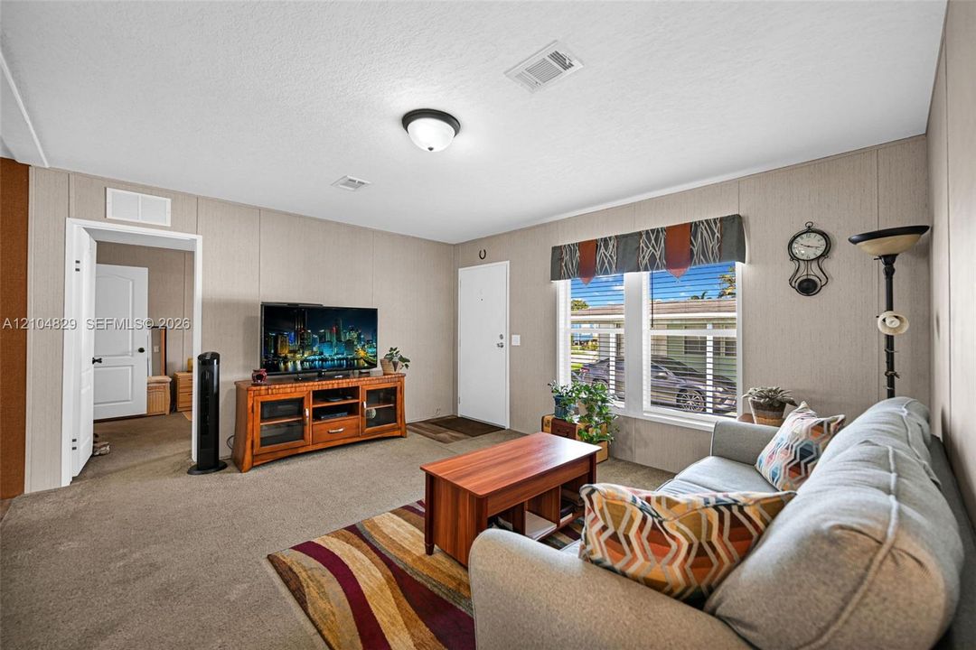 Neutral-toned wall paneling, wall-to-wall carpeting, dual-pane windows, and a flush-mount ceiling light fixture