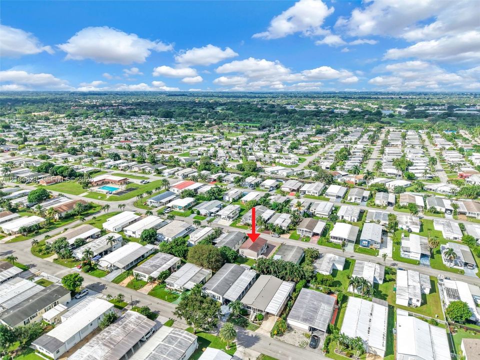 Aerial view of a residential property situated in a suburban community, featuring established greenery and paved streets