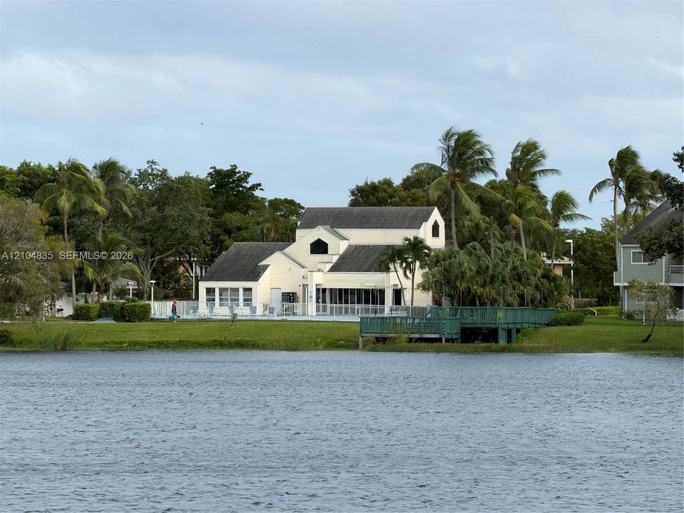 Waterfront exterior featuring a swimming pool, wooden deck, manicured lawn, and mature palm trees