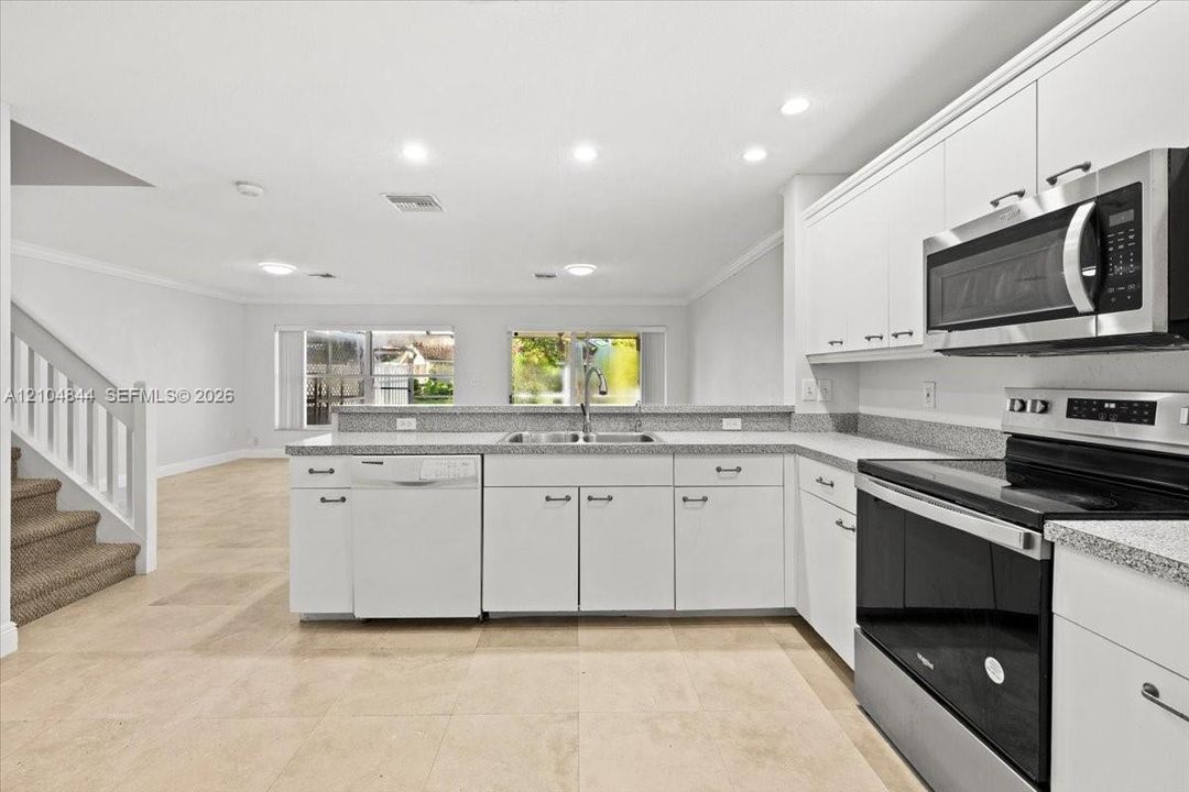Kitchen featuring white cabinetry, stone-finish countertops, stainless steel appliances, recessed lighting, and tile flooring
