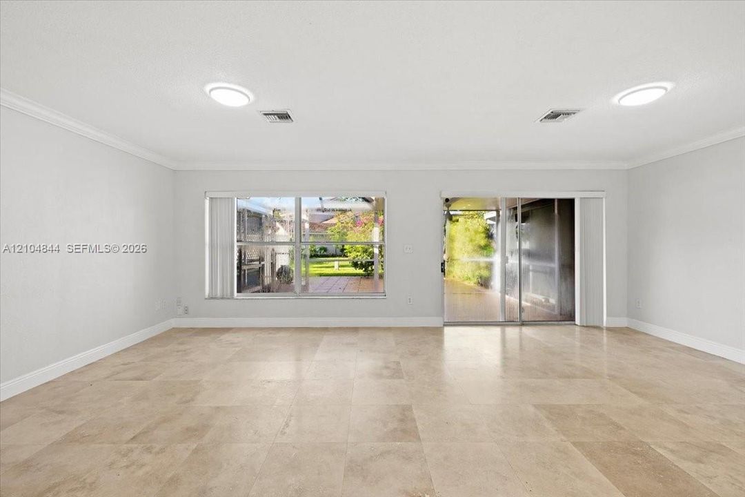 Neutral-toned tile flooring, recessed ceiling lighting, crown molding, expansive windows, and glass sliding door