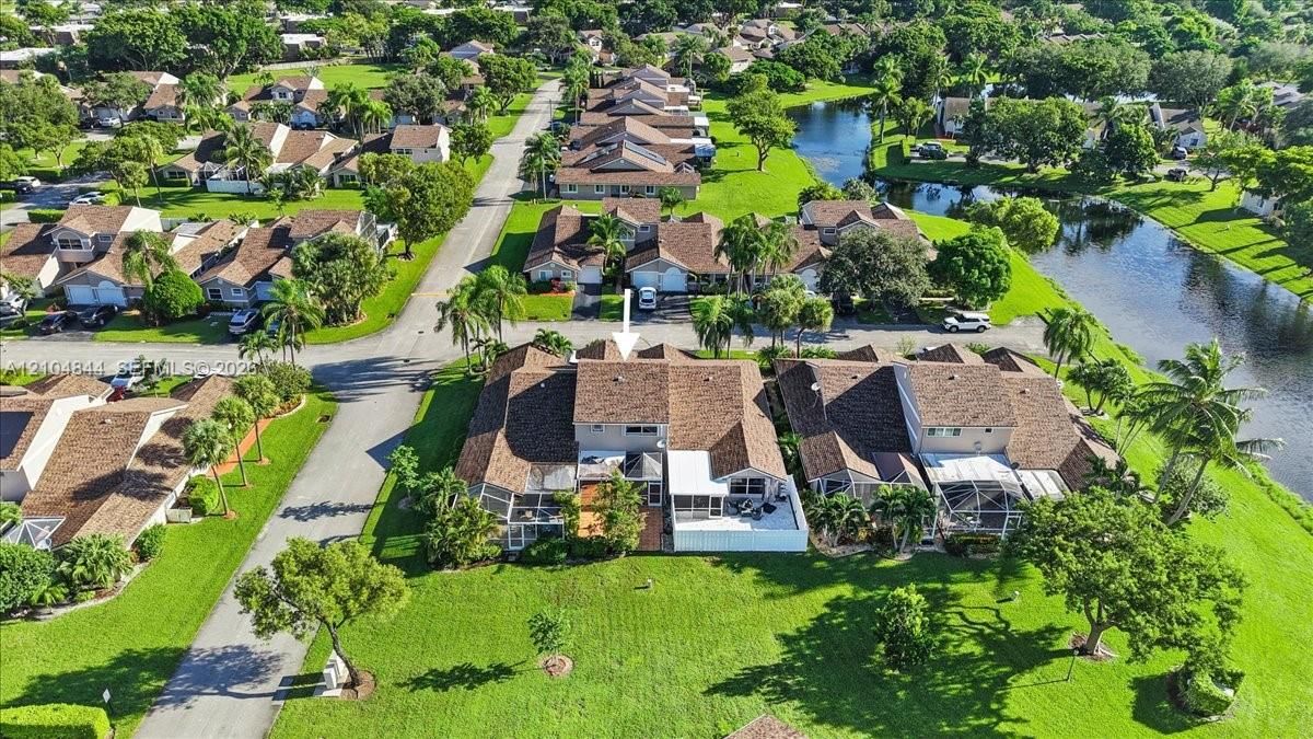 Multi-level townhome featuring a shingle roof, rear-facing screened-in patio, and direct access to expansive green space and water frontage