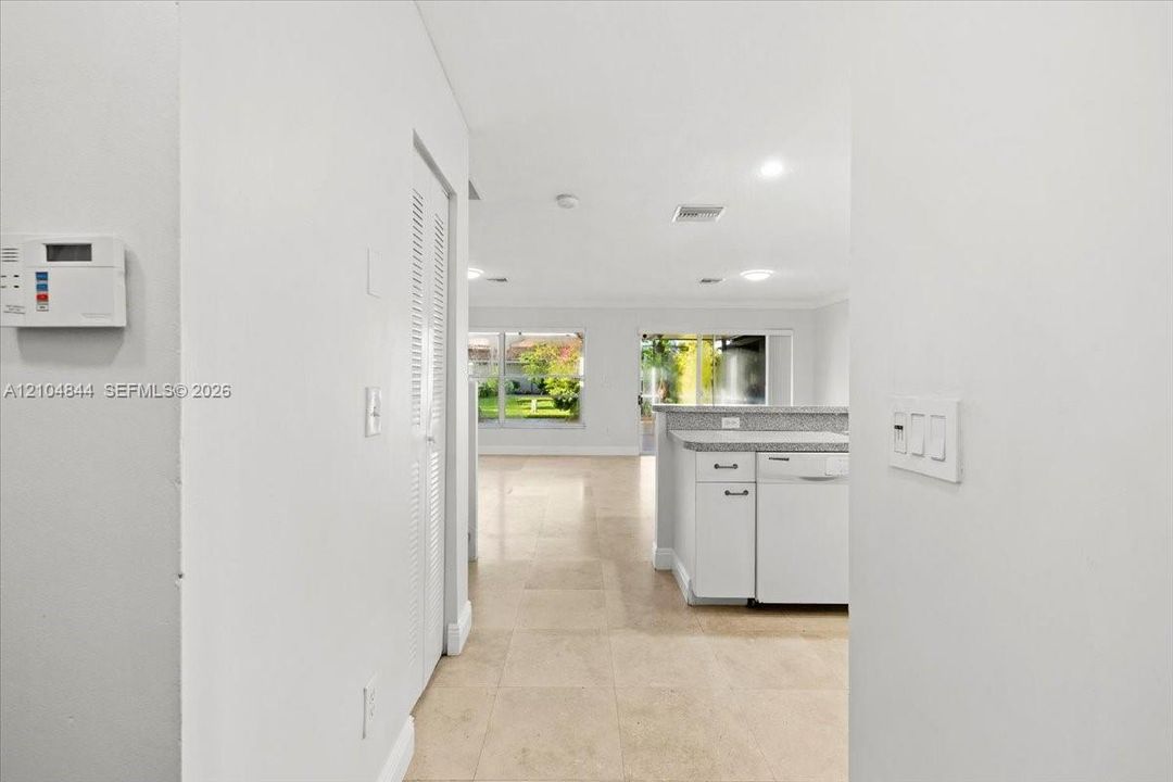 Interior space featuring large-format tile flooring, white cabinetry with stone-surface countertops, recessed lighting, and sliding glass doors
