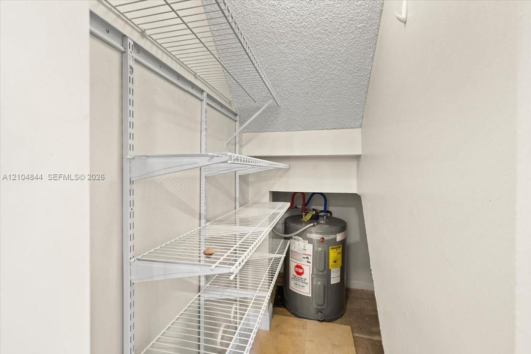 Storage area featuring white wire shelving and a water heater