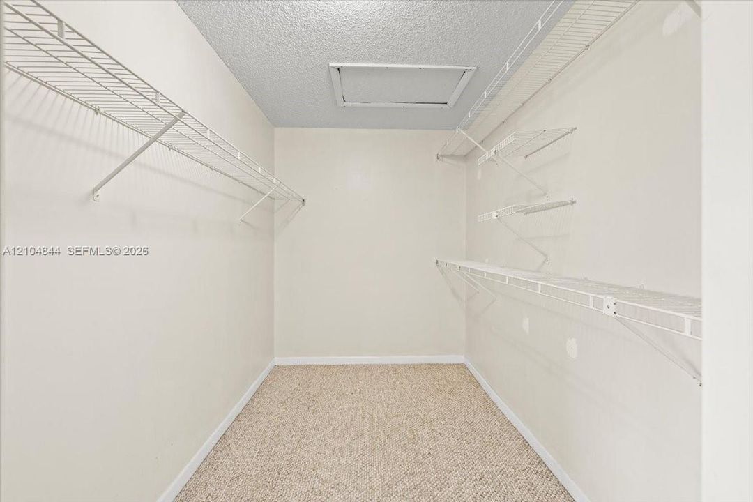Walk-in closet featuring multi-level white wire shelving and neutral wall-to-wall carpeting
