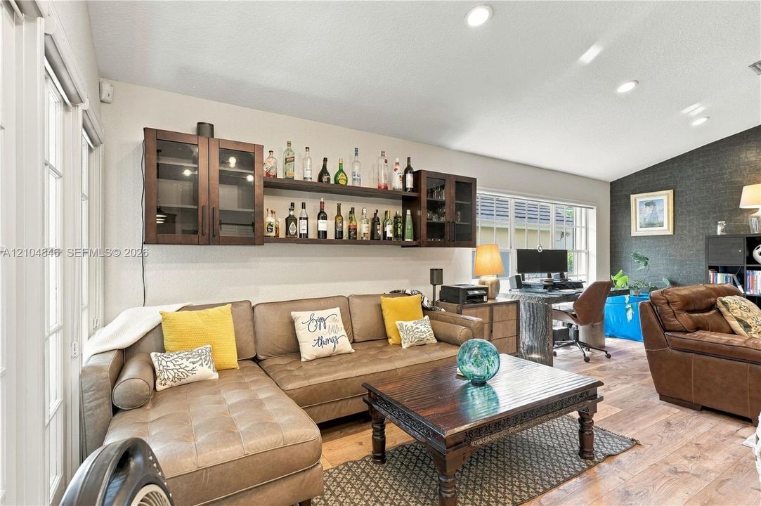 Built-in wood wall cabinetry with open shelving, wood-finish flooring, recessed lighting, and a textured accent wall