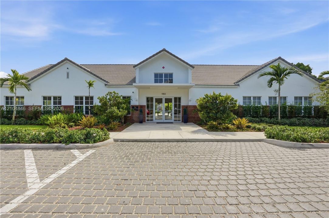 Stucco and brick facade featuring a gabled roofline, concrete tile roofing, glass-paned double entry doors, and a decorative interlocking paver parking area