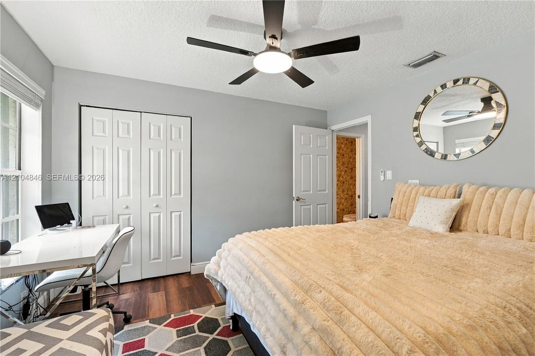 Bedroom featuring wood-finish flooring, a multi-blade ceiling fan with integrated lighting, and a dual-panel closet door