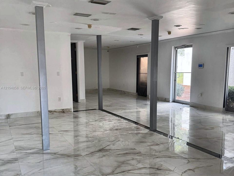 Polished stone-finish tile flooring, recessed ceiling lighting, and structural support columns