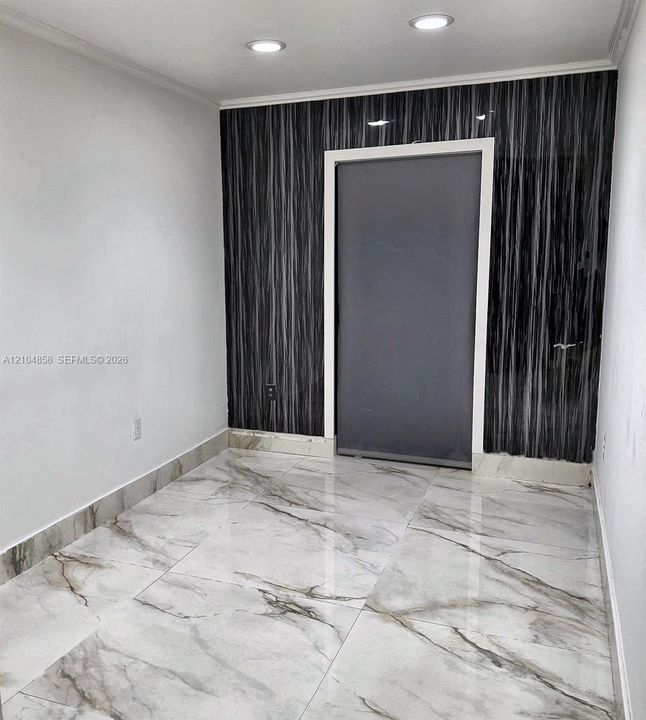 Large-format stone-patterned tile flooring, decorative vertical-striped wall paneling, and recessed ceiling lighting