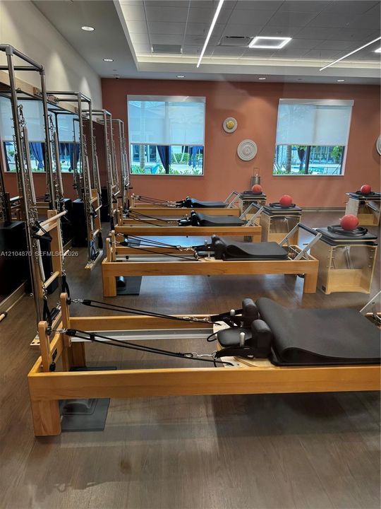 Fitness room featuring wood-finish flooring, recessed linear lighting, full-length mirrors, and neutral wall tones