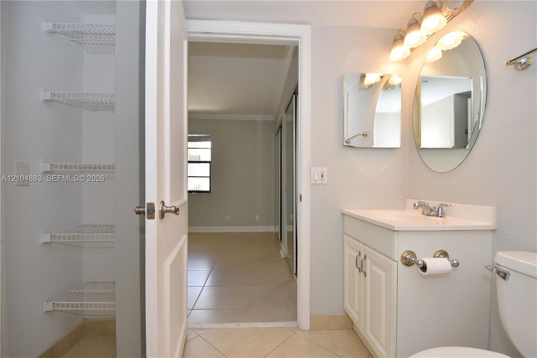 Bathroom vanity with integrated sink, tiled flooring, and wall-mounted mirror