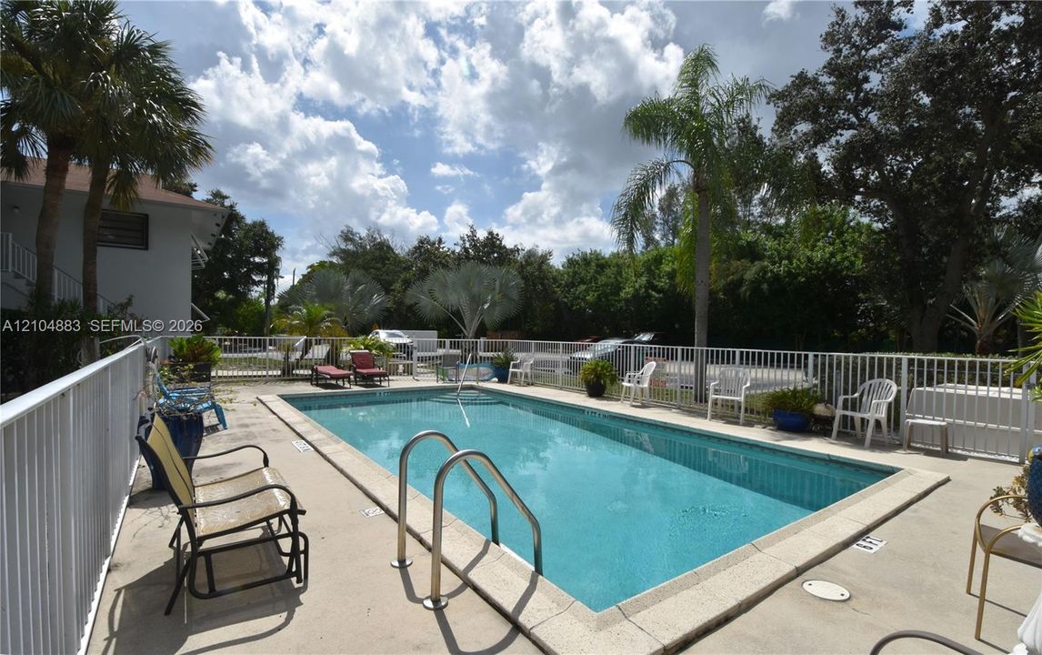 Swimming pool with concrete surround and white fencing