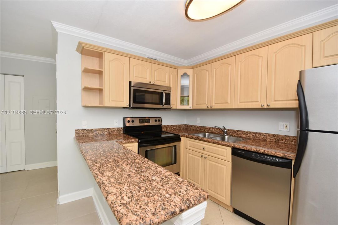 Kitchen featuring honey-toned cabinetry, stainless steel appliances, speckled stone-finish countertops, and a built-in breakfast bar