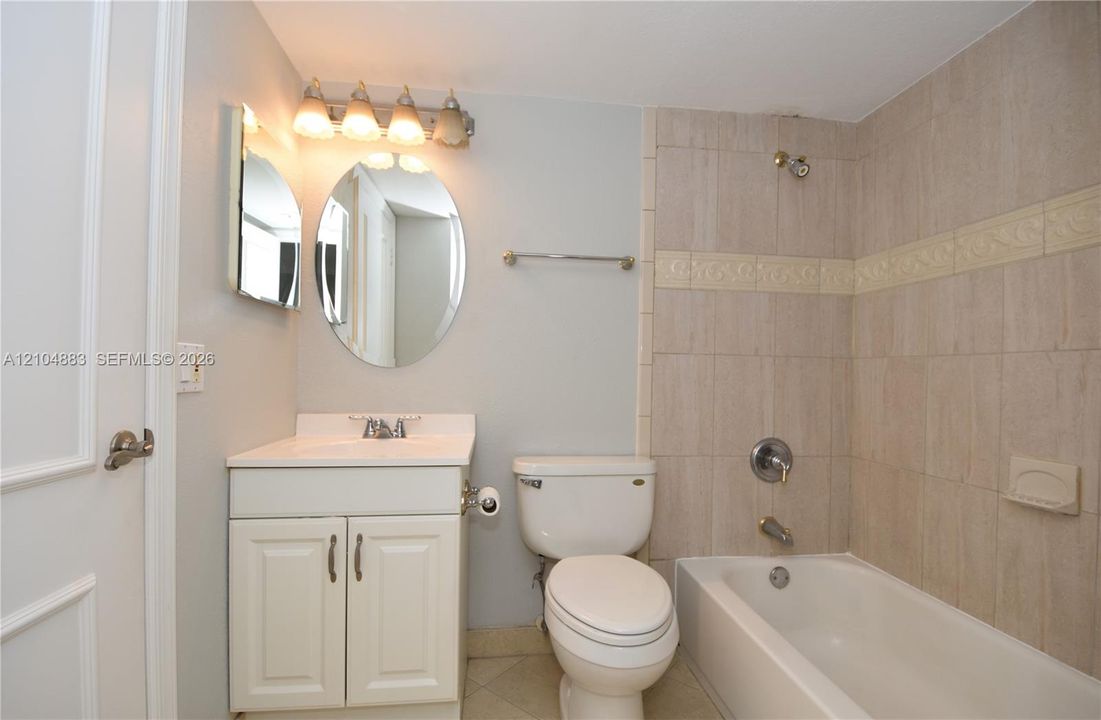Bathroom with a vanity, rectangular sink, and tile-surround bathtub