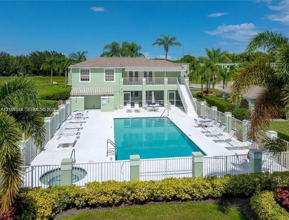 Community pool with a hot tub, surrounded by a white picket fence