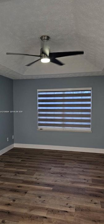 Wood-finish flooring, accent wall, modern ceiling fan, window with horizontal blinds