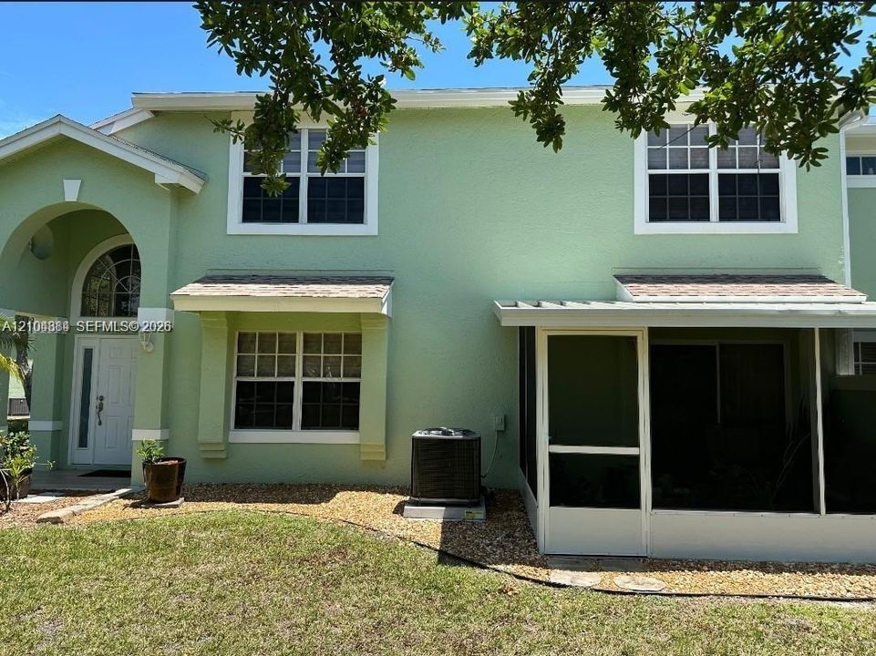 Stucco exterior with white trim, arched entryway, screened porch, and gravel landscaping