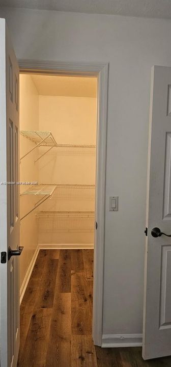 Spacious pantry with multiple wire shelving units and wood-finish flooring