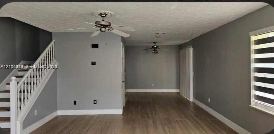 Wood-finish flooring throughout, with a white spindle staircase and ceiling fans with decorative medallions