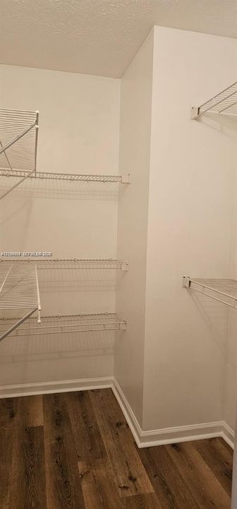 Integrated shelving system with multiple wire shelves, wood-finish flooring, and crisp white walls