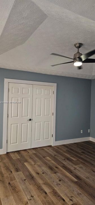 Wood-finish flooring, two-panel bifold closet doors, modern ceiling fan with integrated lighting, and painted walls