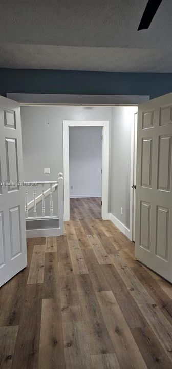 Wood-finish flooring throughout, white paneled doors, and a staircase with white balusters