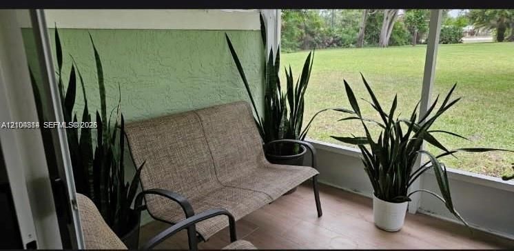 Screened outdoor area with textured green wall, light-toned flooring, and expansive exterior green space