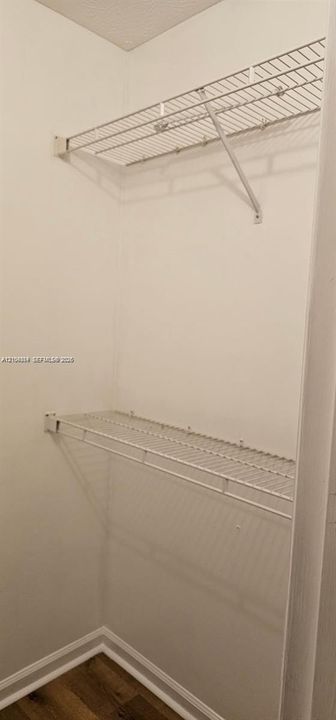 Built-in wire shelving with white finish, wood-finish flooring, and white baseboards