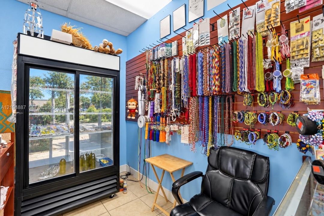 Commercial interior featuring a glass-door refrigeration unit, wood-paneled wall display system with integrated hardware, and ceramic tile flooring