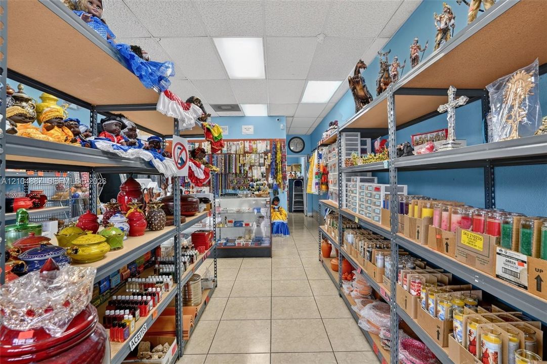 Commercial space featuring industrial metal shelving, neutral tile flooring, recessed ceiling lighting, and a glass-enclosed counter